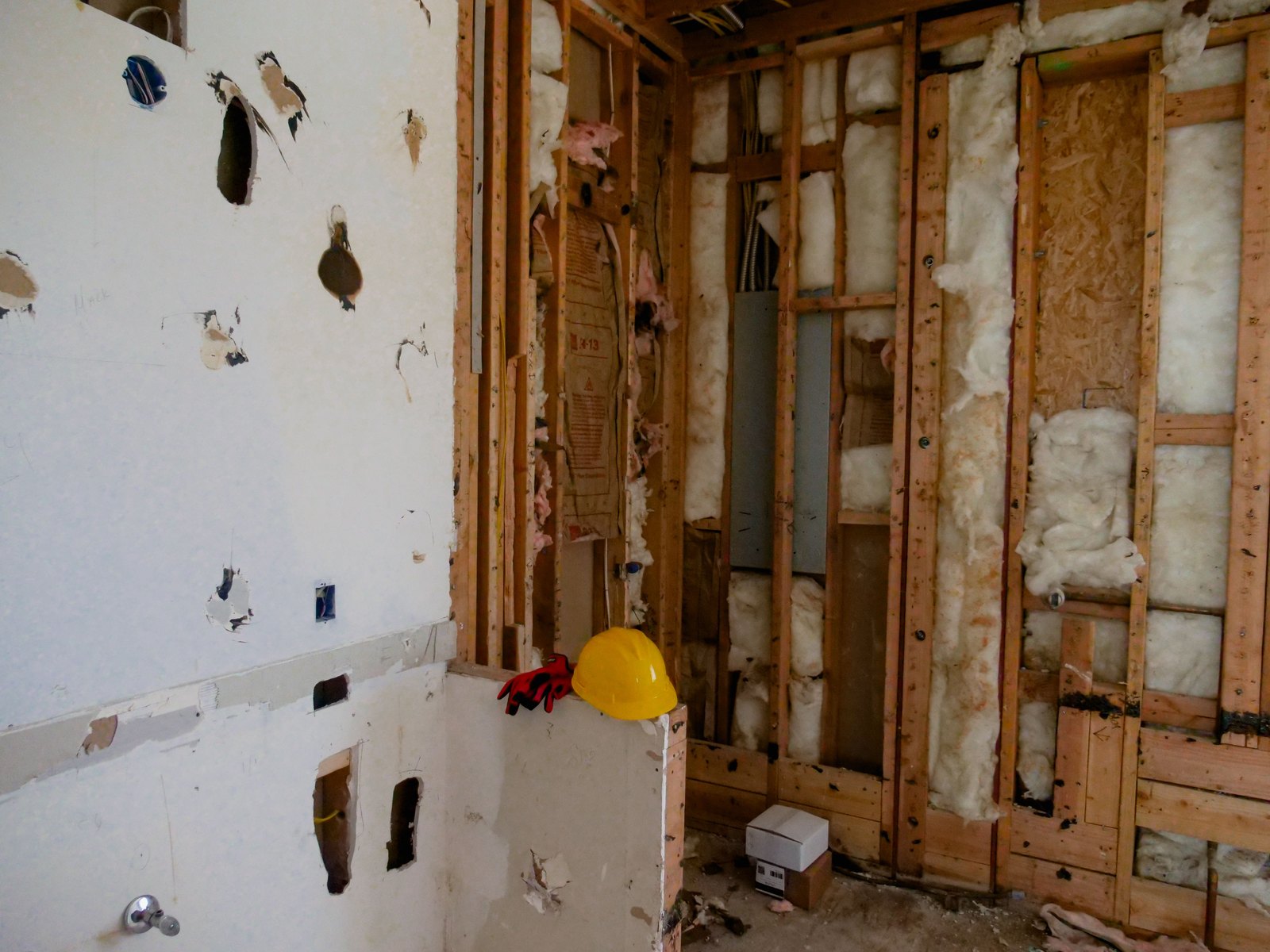 Kitchen wall opened to the framing during a Palo Alto remodel, with the electrical panel and insulation exposed