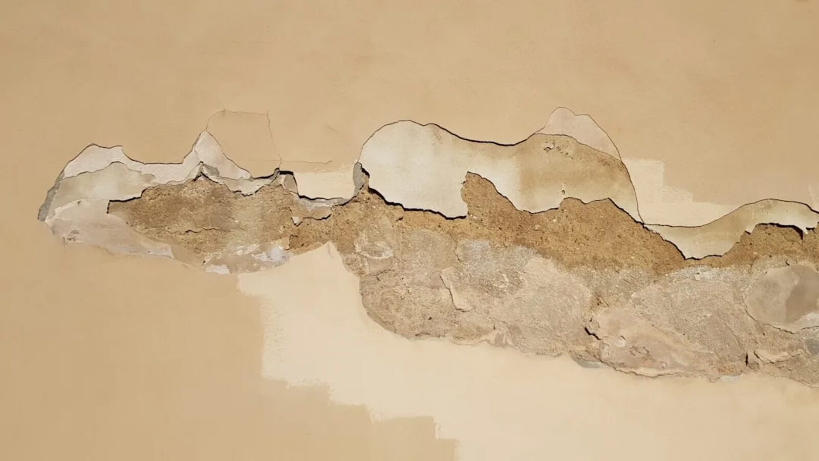 Water-damaged plaster wall where a small leak kept working until the repair grew structural